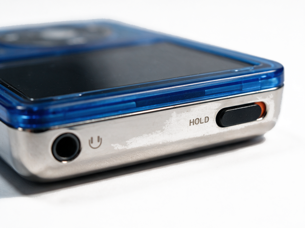 Voltage &mdash; top edge, headphone jack and hold switch, translucent electric blue iPod Classic.